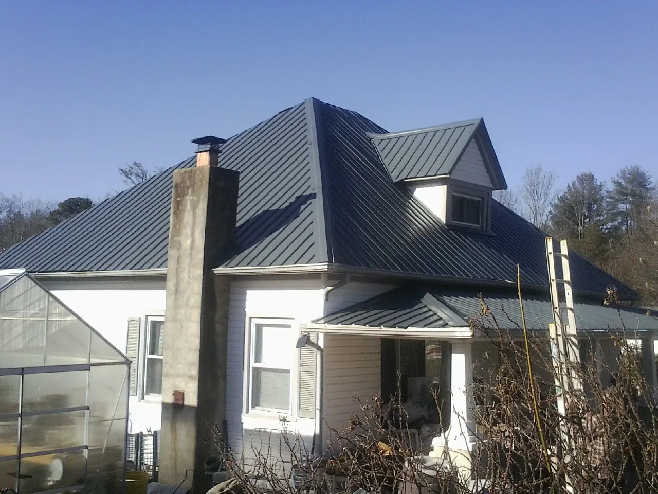 Dark blue standing seam metal roof on a white farmhouse with dormer — Slate & Tile Roof Repair by Roofing Brothers in Canby