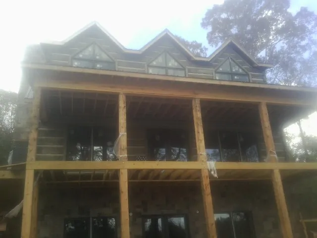 Dormers and porch framing on a large log home under construction — Roof Coating work by our crew in Canby