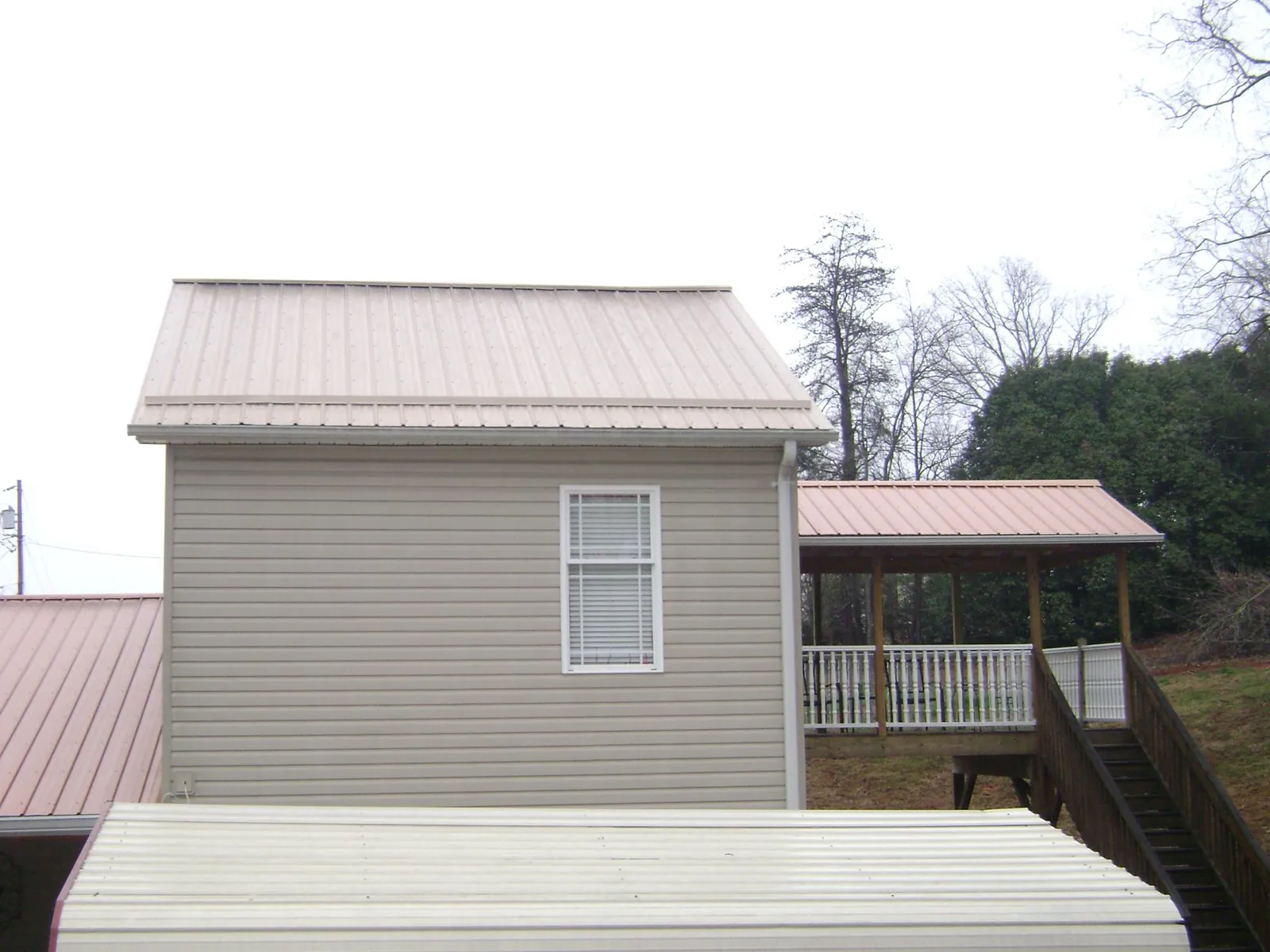 Tan metal roofs on a two story addition and attached porch, from a Roof Replacement job in Canby